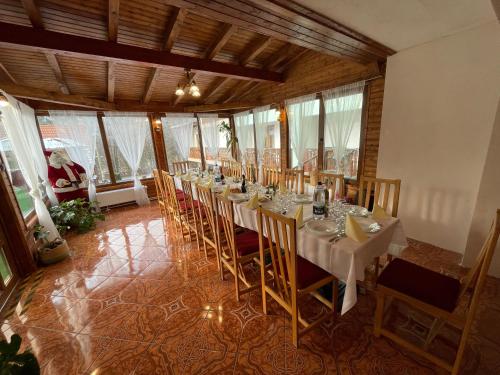 Cette chambre comprend une grande table avec des chaises et des fenêtres. dans l'établissement Pensiunea Olt Centrum/ Olt Centrum panzió, à Băile Tuşnad