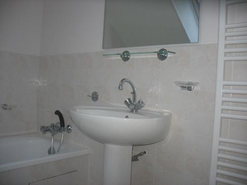 La salle de bains est pourvue d'un lavabo, d'un miroir et d'une baignoire. dans l'établissement Gîte 3 avec piscine - plage 3kms, à Clohars-Carnoët
