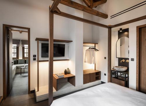 a bedroom with a bed and a tv and a bathroom at Unedo All Seasons Boutique Hotel in Palaios Panteleimon