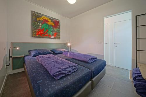 a bedroom with a bed with purple pillows and a painting at Domaine Long Pre in Stavelot