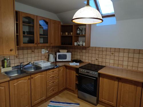 a kitchen with wooden cabinets and a sink and a microwave at Privát Majo in Liptovský Mikuláš