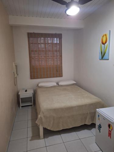 a bedroom with a bed and a window at Pousada Areias Brancas in Búzios