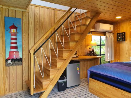 a wooden staircase in a bedroom with a lighthouse on the wall at บ้านนกฮูกอิงไม้ ริมเล in Ban Khlong Sai