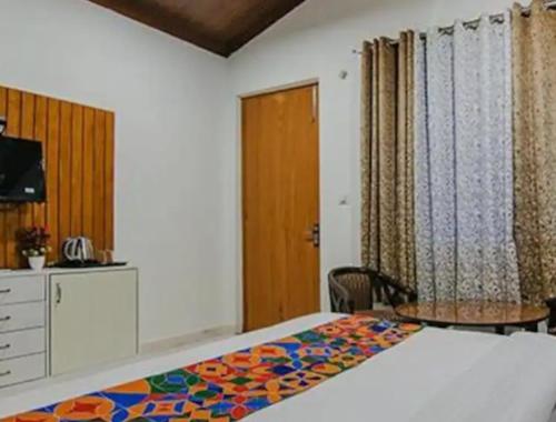 ラムナガルにあるCorbett Jungle Breeze Resortのベッドルーム1室(ベッド1台、デスク、テーブル付)