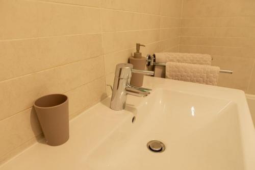 um lavatório branco na casa de banho com uma chávena em Au pied de la Tour Eiffel résidence familiale 2bdr em Paris