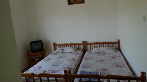 two twin beds in a room with a tv at Marina's Rooms in Lipsoi