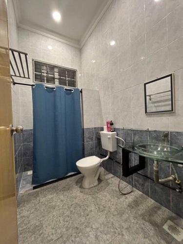 baño con aseo y cortina de ducha azul en HomeStay Tawau en Tawau