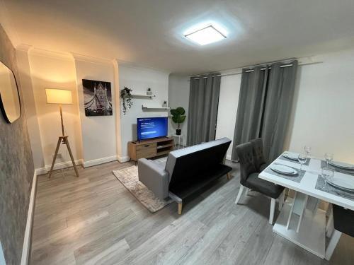ein Wohnzimmer mit einem Sofa, einem Tisch und einem TV in der Unterkunft Contemporary Style in the Heart of London in London