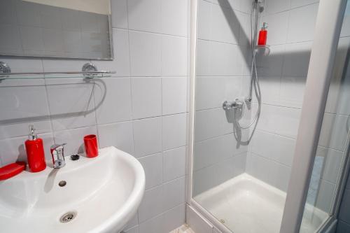 a white bathroom with a shower and a sink at VacationClub - Ski Lodge Szczyrk Pokój 1 & 2 in Szczyrk