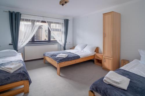 een slaapkamer met 2 aparte bedden en een raam bij VacationClub - Ski Lodge Szczyrk Pokój 1 & 2 in Szczyrk