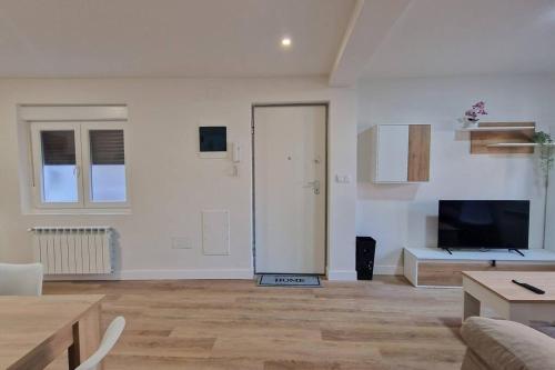 - un salon blanc avec une télévision et un canapé dans l'établissement Apartamento Aires de Tineo, à Oviedo