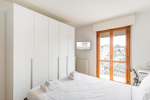 una camera bianca con un letto e una finestra di Padova Station - Bright Apartment with Balcony! a Padova