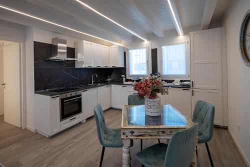 una cocina con armarios blancos y una mesa con sillas. en Camerini Guest House, en Piazzola sul Brenta