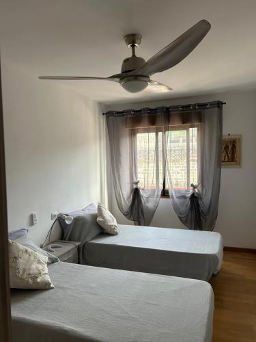 Un dormitorio con dos camas y un ventilador de techo. en La Casita de Gio., en Tazacorte