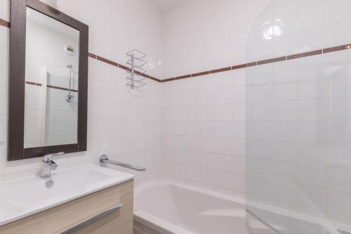 une salle de bain avec une baignoire, un lavabo et un miroir dans l'établissement Chalet Orée des pistes - Piscine et sauna, aux Orres