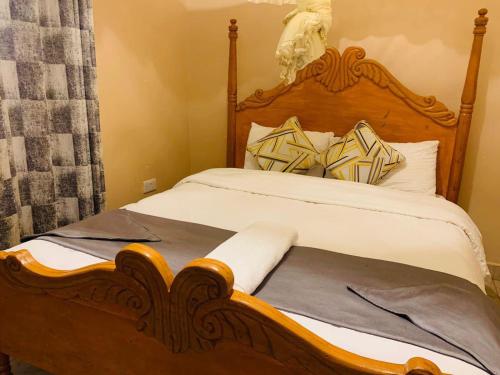 Bett mit einem Kopfteil aus Holz und Kissen in der Unterkunft Villa Serene Hotel in Kitale