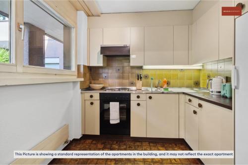 a kitchen with white cabinets and a stove top oven at Beautiful Boutique Apartment DRAHTZUG8 in Zürich