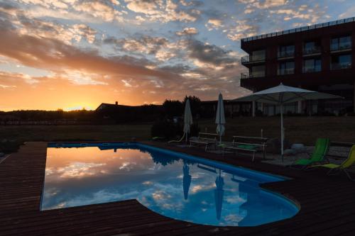 a pool in front of a building with a sunset at K-Triumf Resort in Velichovky