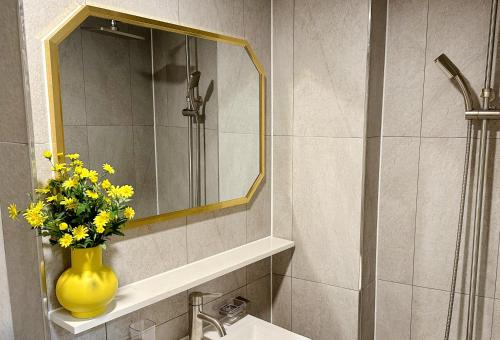 a bathroom with a yellow vase with yellow flowers on a sink at 8 Hotel in Seoul