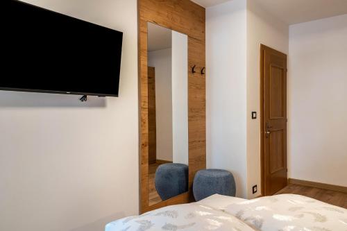 a bedroom with a television and two blue chairs at Kamerloy Apartments A in Campitello di Fassa
