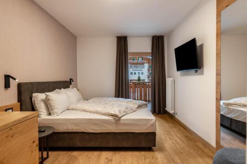 a hotel room with a bed and a television at Kamerloy Apartments A in Campitello di Fassa
