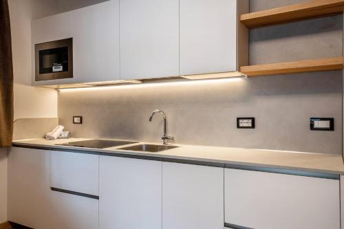 a kitchen with white cabinets and a sink at Kamerloy Apartments A in Campitello di Fassa