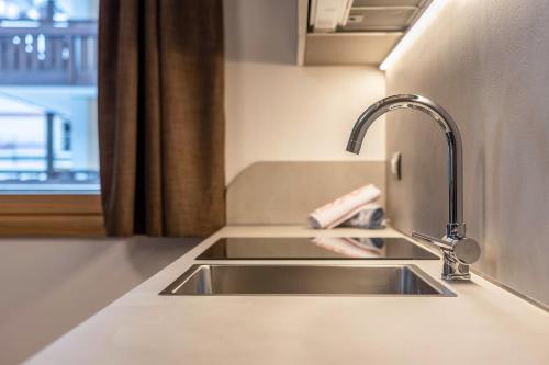 a kitchen counter with a sink and a window at Kamerloy Apartments A in Campitello di Fassa