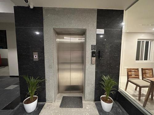 an elevator in a building with two potted plants at Nectar Living - Iris in Hyderabad