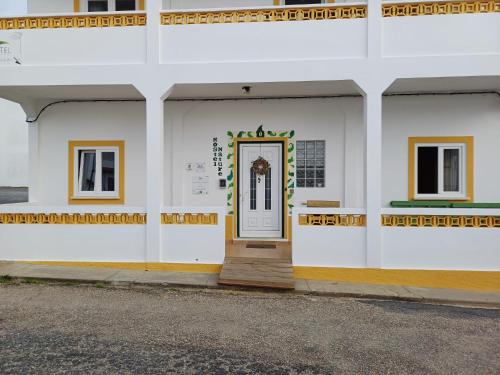 a white building with a door on the side at Hostel Nature in Zambujeira do Mar