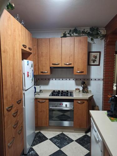 a kitchen with wooden cabinets and a white refrigerator at Precioso apartamento con vistas al Mar. in La Cala de Mijas