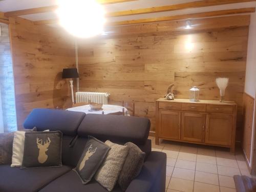 sala de estar con sofá azul y paredes de madera en Appartement 4 personnes tout équipé VOSGES. en Rochesson