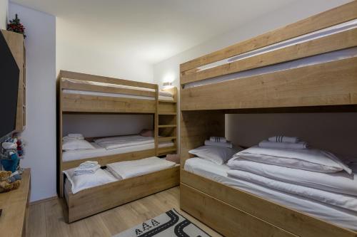 two bunk beds in a room with white sheets at Casa Valley Paradiso - Jahorina in Jahorina