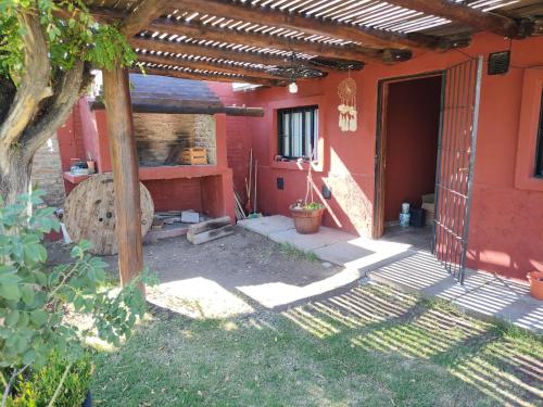 een patio van een rood huis met een houten tafel bij F R F departamentos turisticos Nº 2 in San Rafael