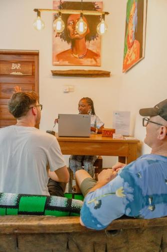 a group of people sitting at a table with a laptop at Shoki Shoki Hotel Stone Town in Zanzibar City