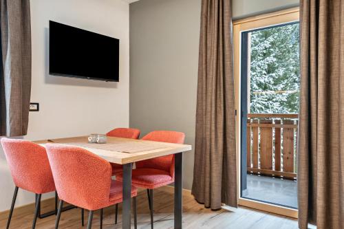 una sala da pranzo con tavolo, sedie e una finestra di Kamerloy Apartments B a Campitello di Fassa