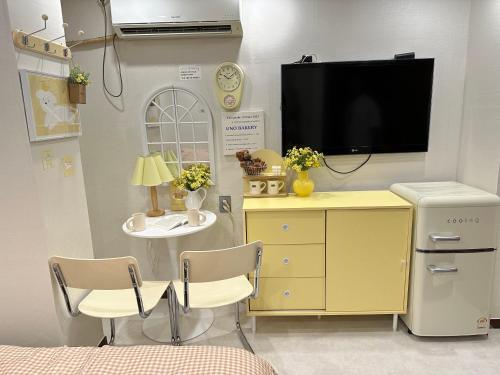 a bedroom with a tv and a yellow dresser with two chairs at 8 Hotel in Seoul