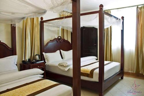 a bedroom with two canopy beds with white sheets at Island Paradise Inn in Ngambo