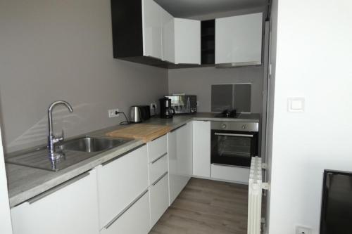 a kitchen with white cabinets and a sink at Les Dunes Blanches in Le Crotoy