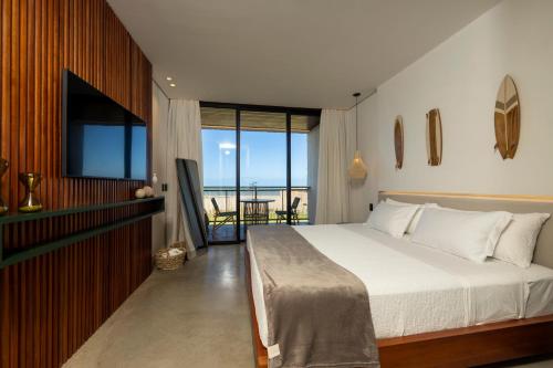 um quarto com uma cama, uma televisão e uma varanda em Nanii Hotel em São Miguel do Gostoso
