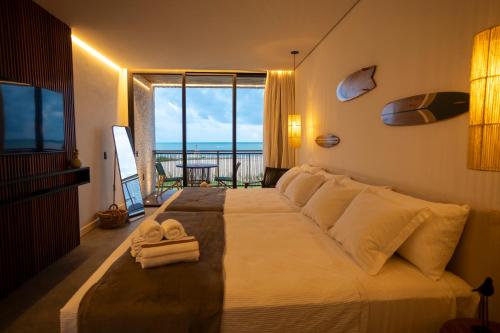 a bedroom with a large bed with a view of the ocean at Nanii Hotel in São Miguel do Gostoso