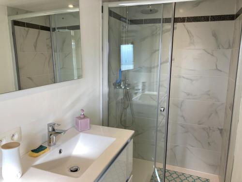 een witte badkamer met douche en wastafel bij Bel Acacia in De Haan