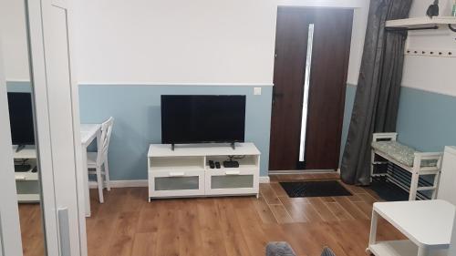 a living room with a television on a white cabinet at Apartamenty Tylicki Poranek in Tylicz