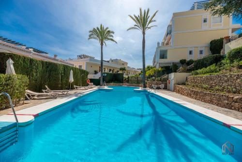 a swimming pool with palm trees and a building at Newly Refurbished 2 BDRM Amazing Complex w Pools in Marbella