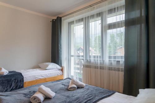 two beds in a room with a large window at VacationClub - Ski Lodge Szczyrk Pokój 3 in Szczyrk