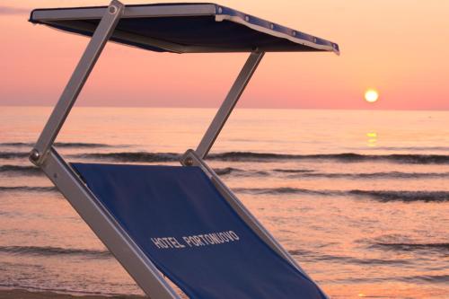 a lifeguard chair sitting on the beach with the sunset at Hotel Portonuovo in Vieste