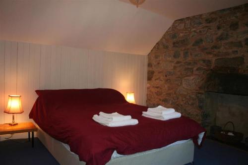 a bedroom with a red bed with towels on it at Barrachandroman Farmhouse in Lochbuie