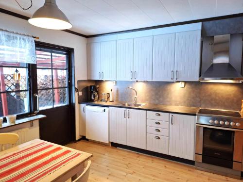 - une cuisine avec des placards blancs, un évier et une table dans l'établissement Vakantiewoning in Småland Zuid-Zweden, à Hjältevad