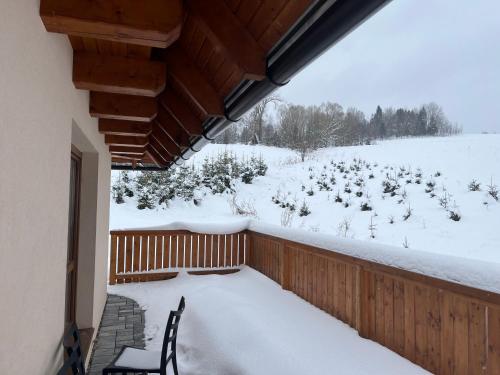 a snow covered balcony with a chair and a yard at Chata u Jána in Zákamenné