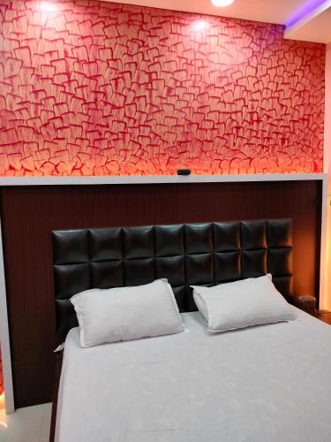 - une chambre avec un lit et un mur rouge dans l'établissement HOTEL GANESH PALACE, à Aurangābād