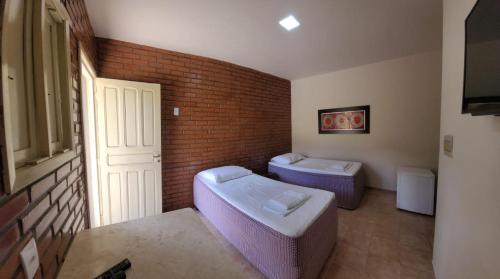 a bathroom with two toilets and a brick wall at Pousada Aquarela in Guamaré